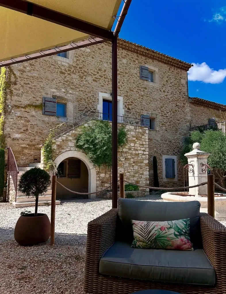 Cour provençale aménagée en gravier avec espace détente devant une bâtisse ancienne en pierre