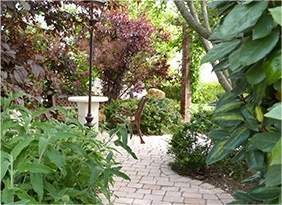 Allée pavée dans un jardin paysager avec plantes luxuriantes et coin détente ombragé