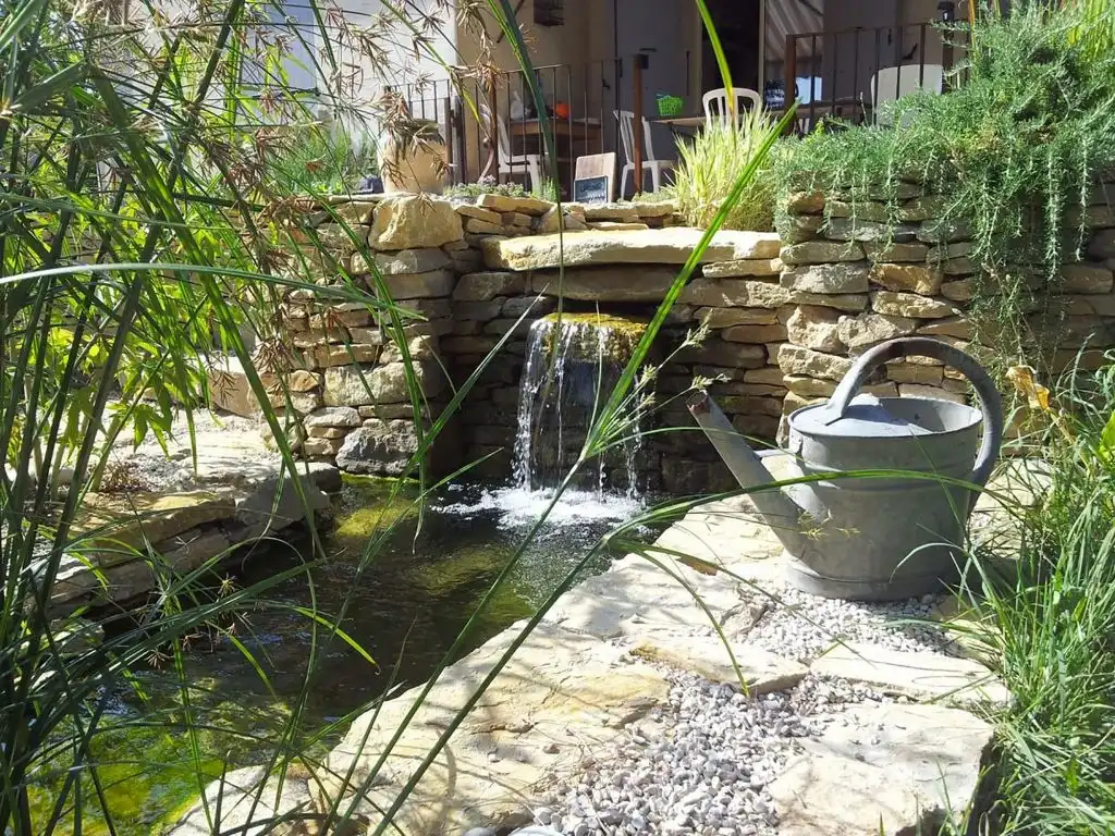 Bassin de jardin avec petite cascade en pierre sèche et arrosoir décoratif