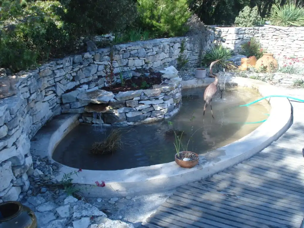 Bassin de jardin en pierre sèche avec cascade et terrasse en bois