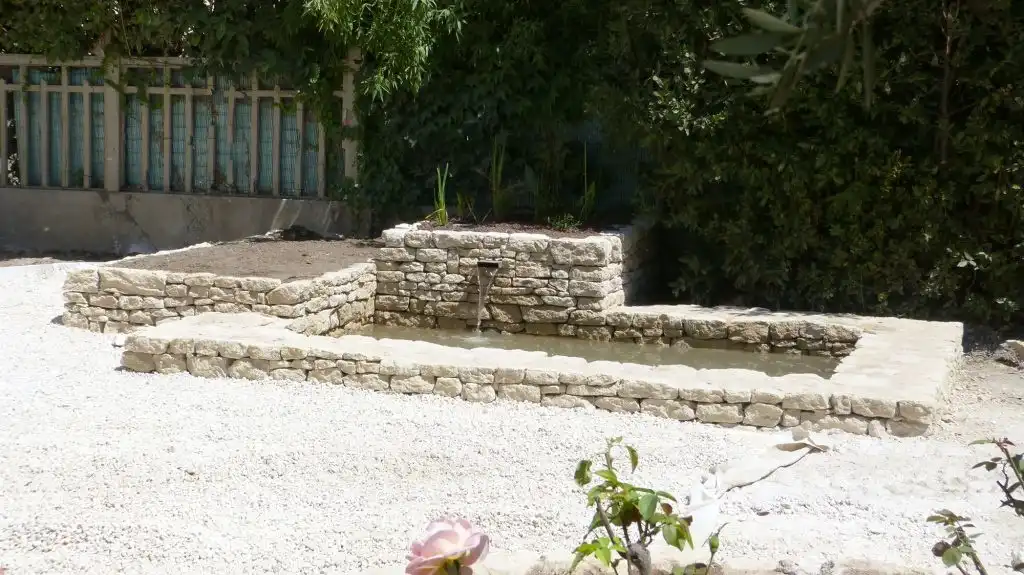Bassin en pierre sèche dans un jardin minéral avec petit écoulement d’eau