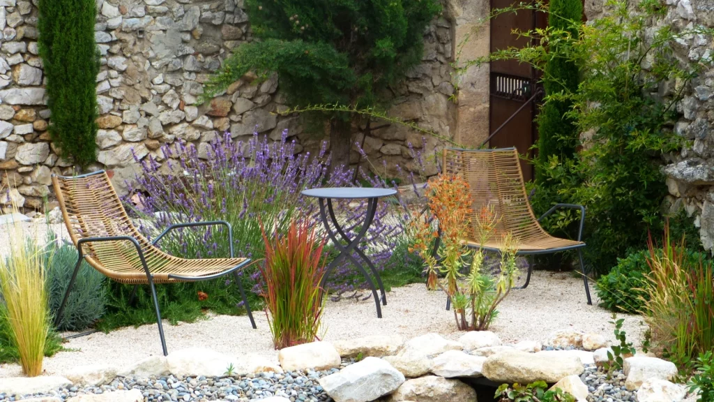 Coin détente dans un jardin méditerranéen avec fauteuils, table, lavande et gravier