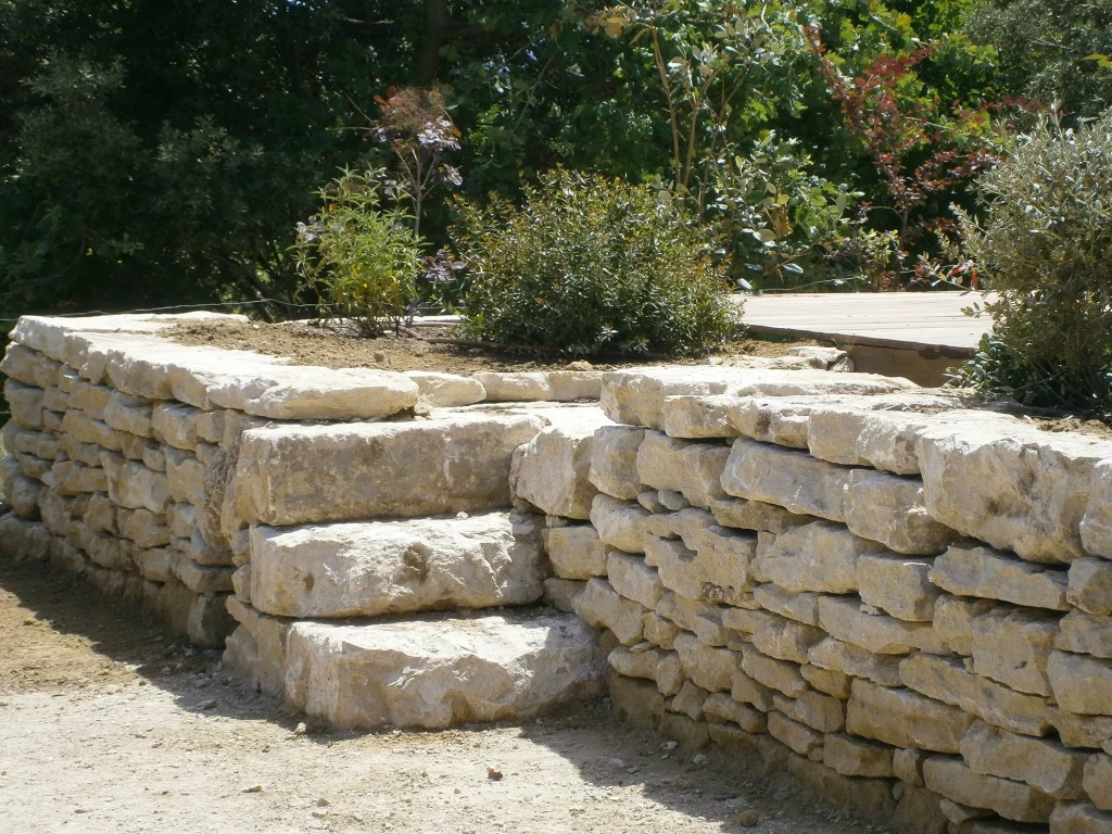 Escalier en pierre naturelle intégré dans un muret en pierre sèche dans un jardin