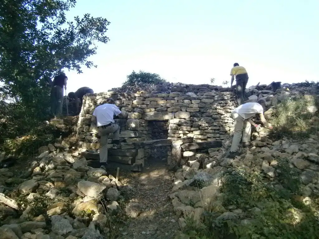 Travaux de restauration d’une borie en pierre sèche par des artisans
