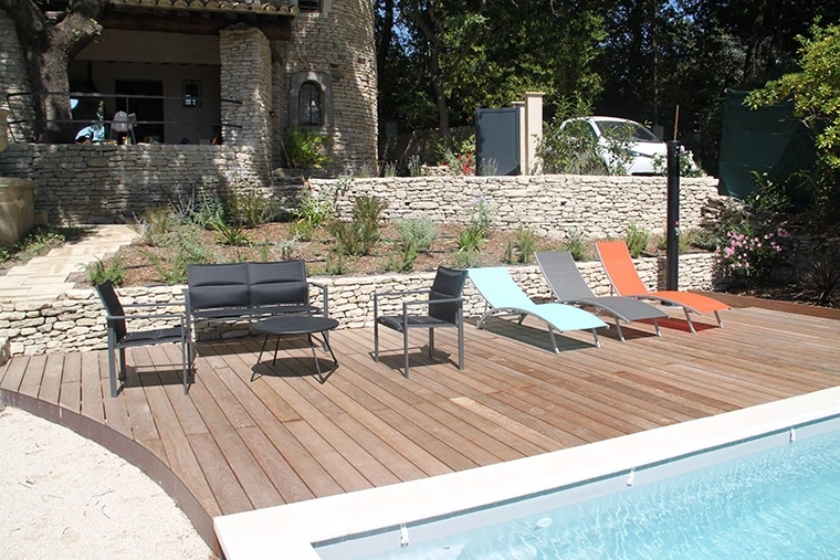 Terrasse en bois avec piscine, mobilier de jardin et aménagement paysager en pierre