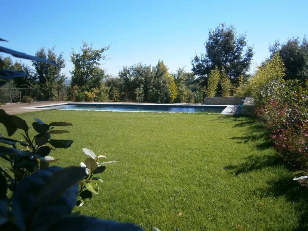 Aménagement du jardin de la Maison Magnarelle à Maubec avec piscine, pelouse et soutènement en pierre sèche