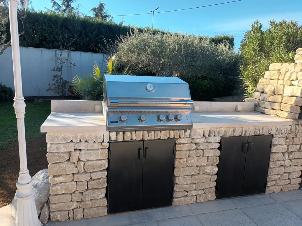 Cuisine extérieure à Cavaillon avec grill à gaz intégré, parement en pierre, plan de travail et rangements métalliques