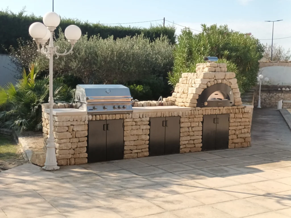 Cuisine extérieure en pierre à Cavaillon avec four à pizza, grill à gaz, plan de travail et armoires métalliques