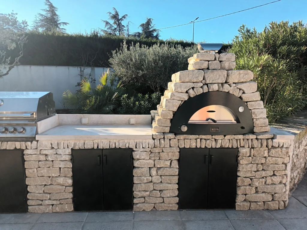 Cuisine extérieure en pierre à Cavaillon avec four à pizza, grill à gaz, plan de travail et rangements métalliques