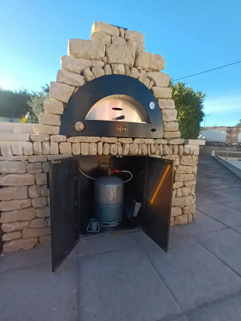 Four à pizza intégré dans une cuisine extérieure en pierre à Cavaillon avec rangement métallique