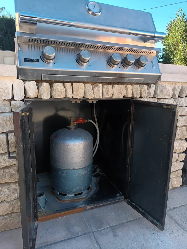Grill à gaz intégré dans une cuisine extérieure en pierre à Cavaillon avec rangement métallique