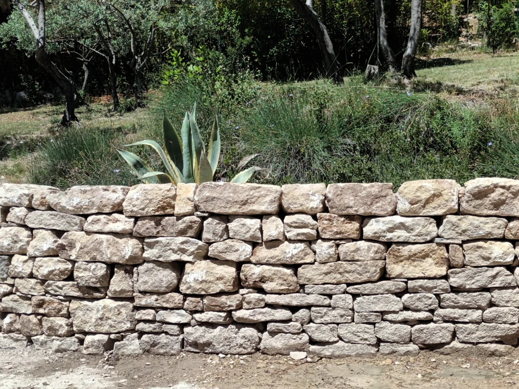 Mur de soutènement en pierre sèche à Velleron intégré dans un jardin méditerranéen