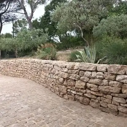 Mur de soutènement en pierre sèche à Velleron longeant l’entrée aménagée de la propriété